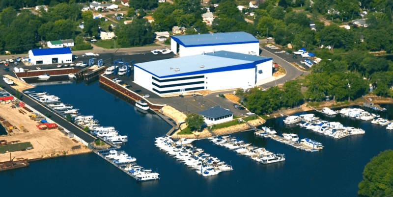 Wide view of American Marine with multiple lines of docked boats showing off in water storing along with pontoon rentals. All boats are submerged in deep blue water making for a beautiful day on the water for boating.