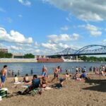 Lots of people crowd on the sand of Pettibone beach along the Mississippi River.