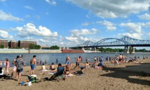 Lots of people crowd on the sand of Pettibone beach along the Mississippi River. 