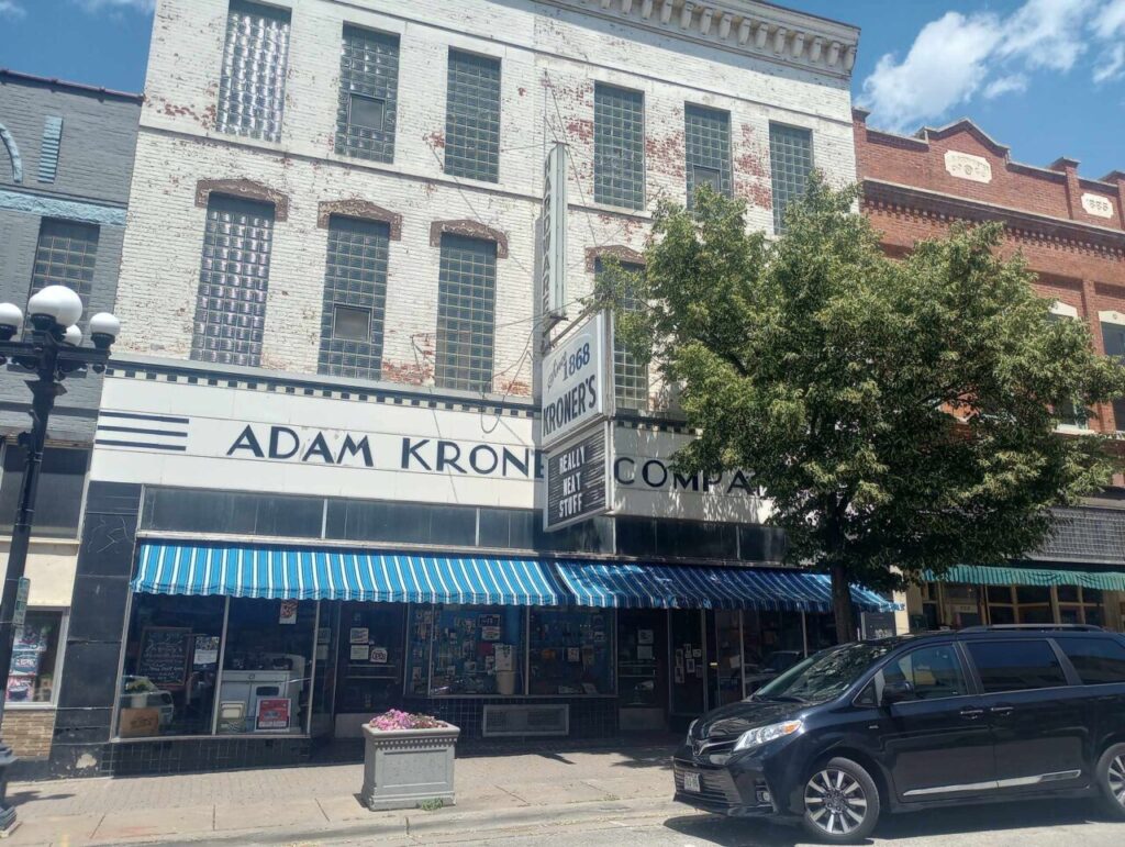 Historic storefront of Kroner’s Hardware in downtown La Crosse, Wisconsin, featuring a vintage sign reading “Since 1868 Kroner’s – Really Neat Stuff,” blue-and-white striped awnings, and the name “Adam Kroner Company” on the façade.