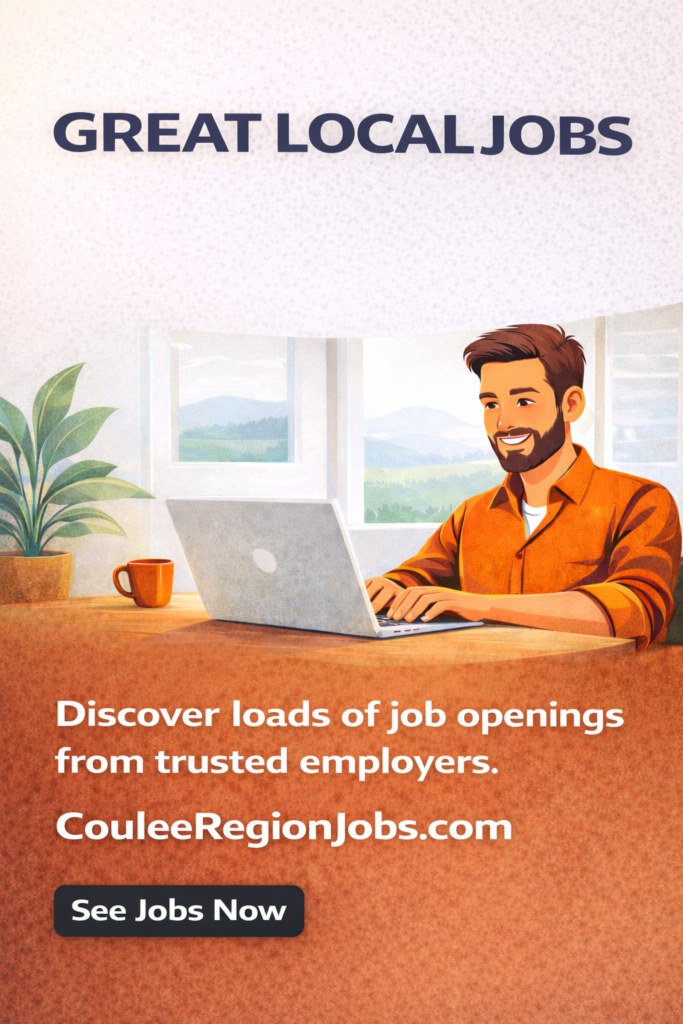 man in an orange sits at a desk working on a laptop and smiling - couleeregionjobs.com