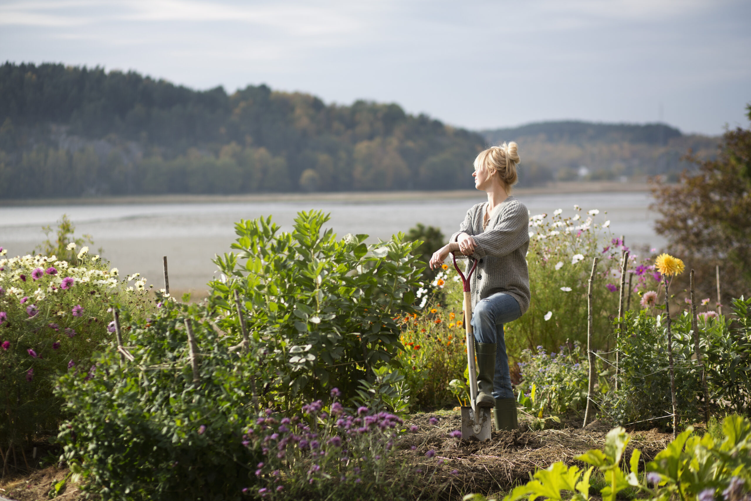 Woman gardening in the Coulee Region. The view she is looking at is of the Mississippi River Valley and the bluffs from her garden.